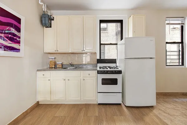 a kitchen with cabinets appliances wooden floor and a window