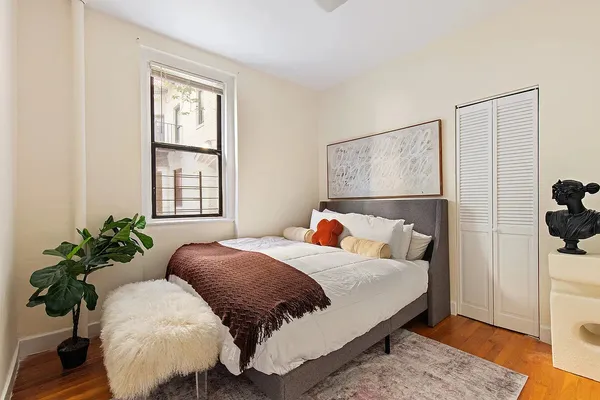 a bed sitting in a bedroom next to a window and potted plant
