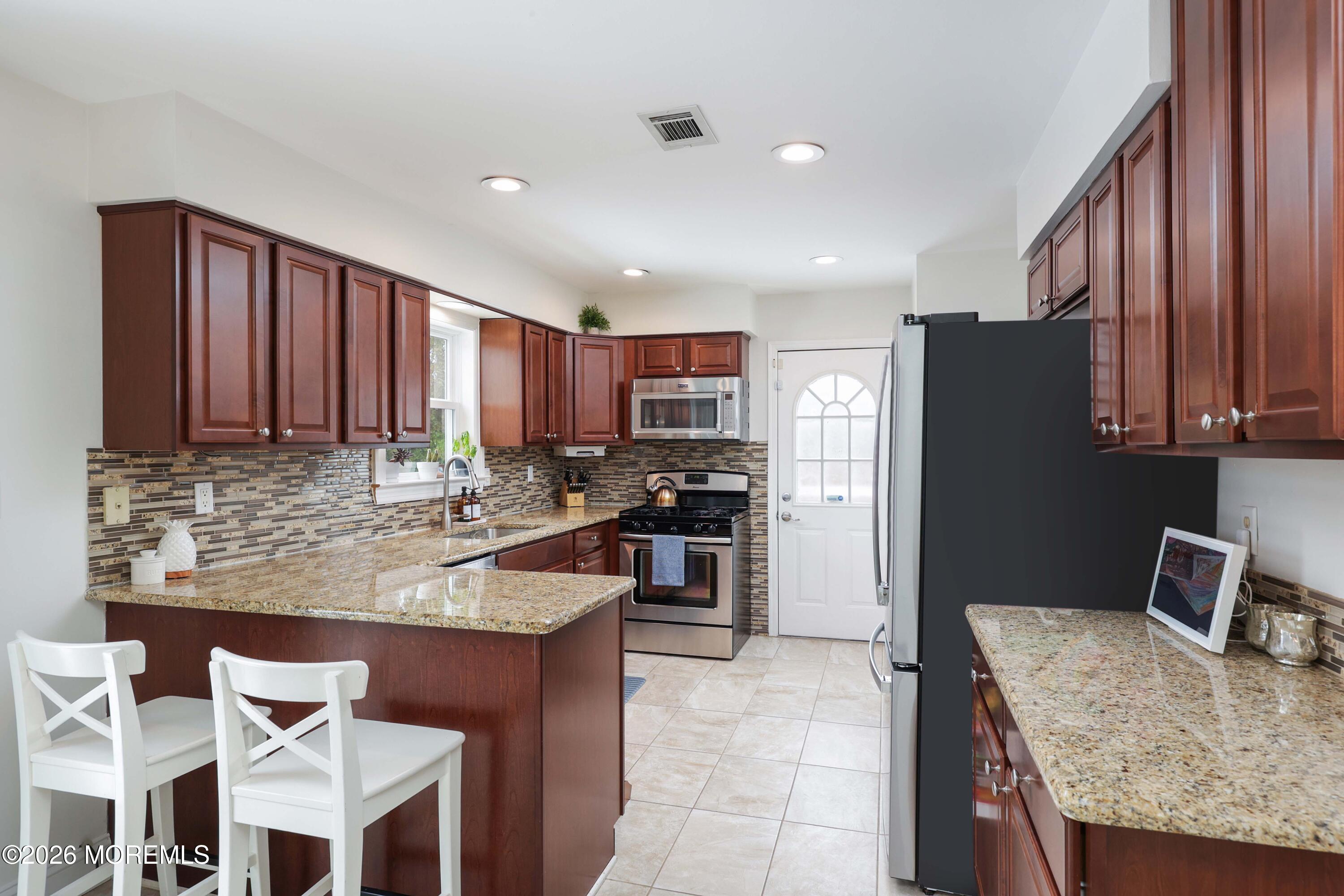 27 Jennifer Drive Howell, NJ 07731 - Photo 7 of 27 a kitchen with granite countertop kitchen island stainless steel appliances a refrigerator sink stove microwave and cabinets
