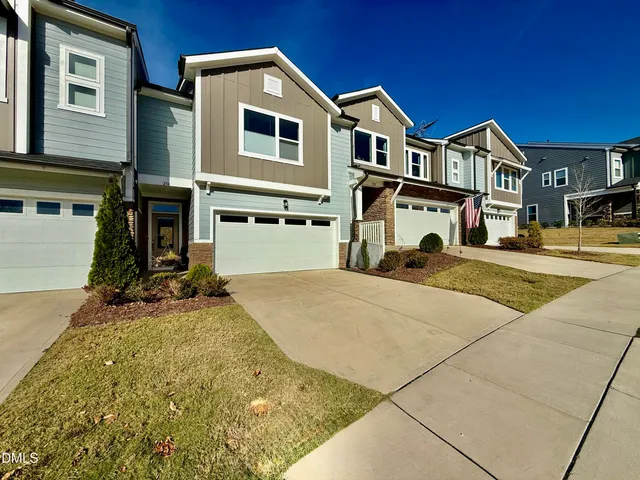 a view of a white house with large windows next to a road
