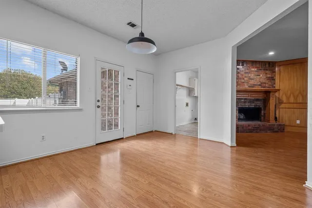 a view of an empty room with window and wooden floor