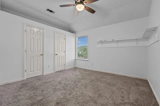 an empty room with fan and windows