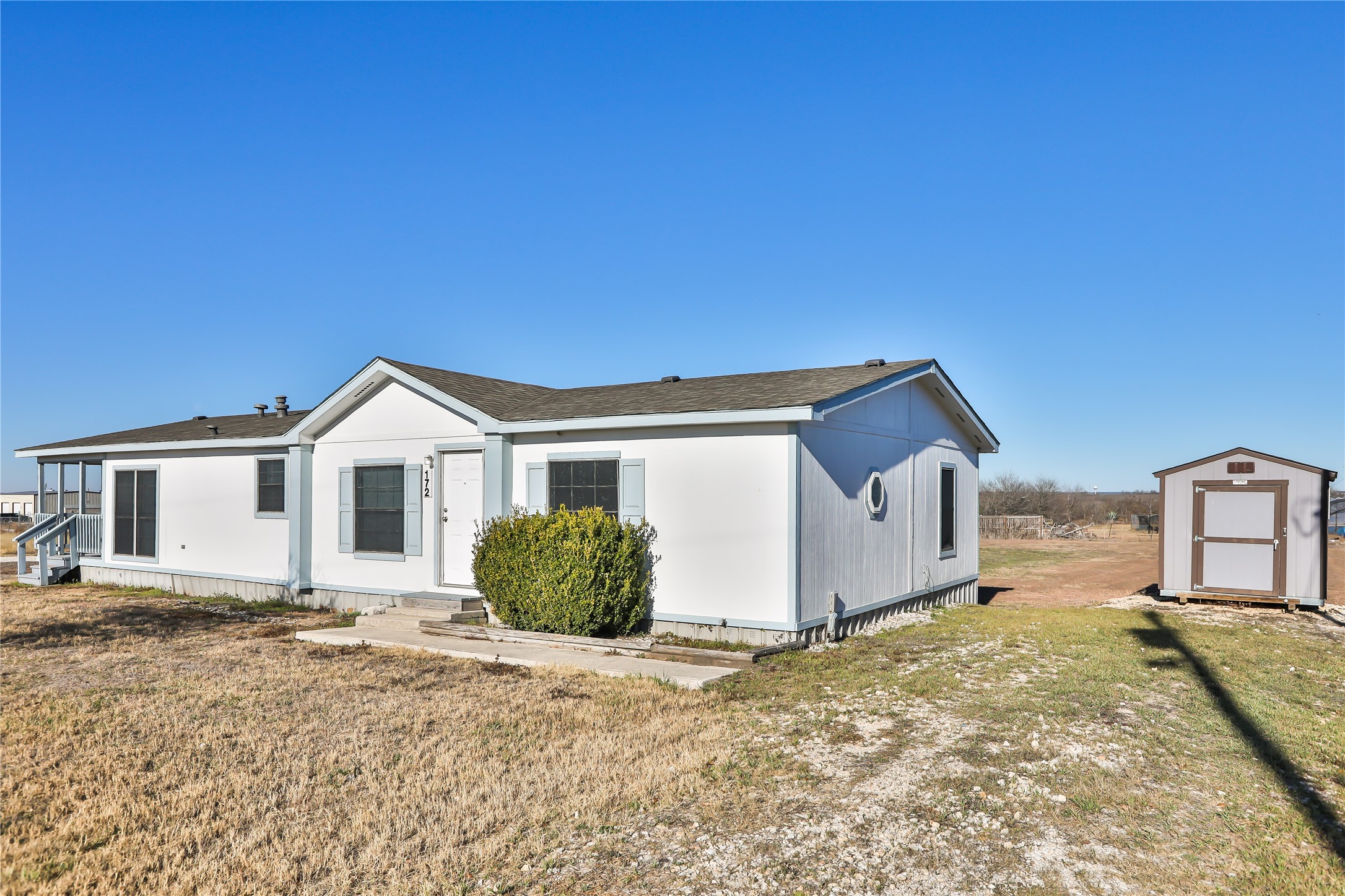 View of front of house with a shed, a front yard, and a shingled roof