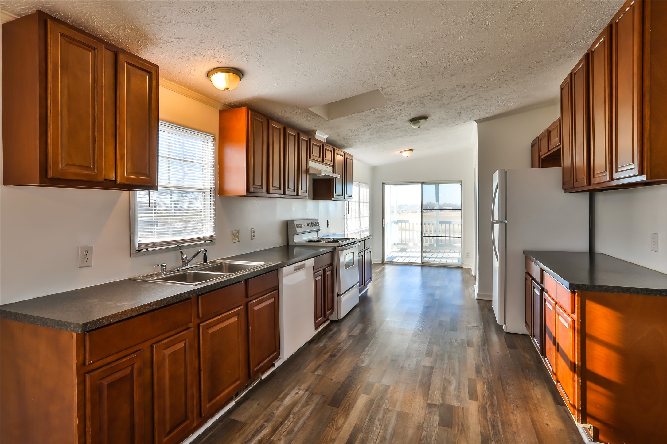 172 Kid Ranch Lane San Marcos, TX 78666 - Photo 5 of 29 Kitchen featuring dark countertops, white appliances, dark wood finished floors, and wood finish cabinetry