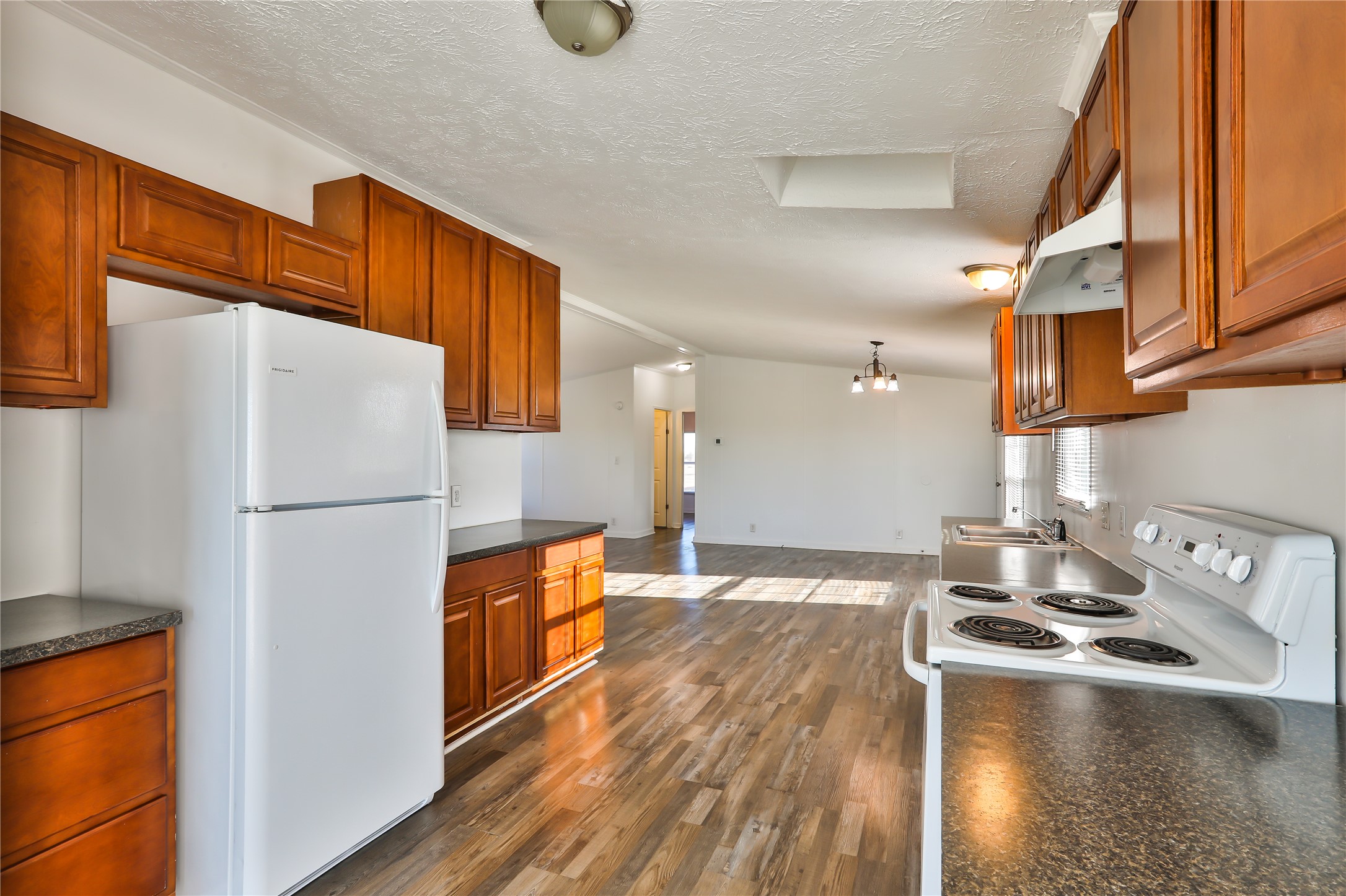 172 Kid Ranch Lane San Marcos, TX 78666 - Photo 6 of 29 Kitchen with white appliances, dark countertops, dark wood-type flooring, wood finish cabinetry, and suspended lighting