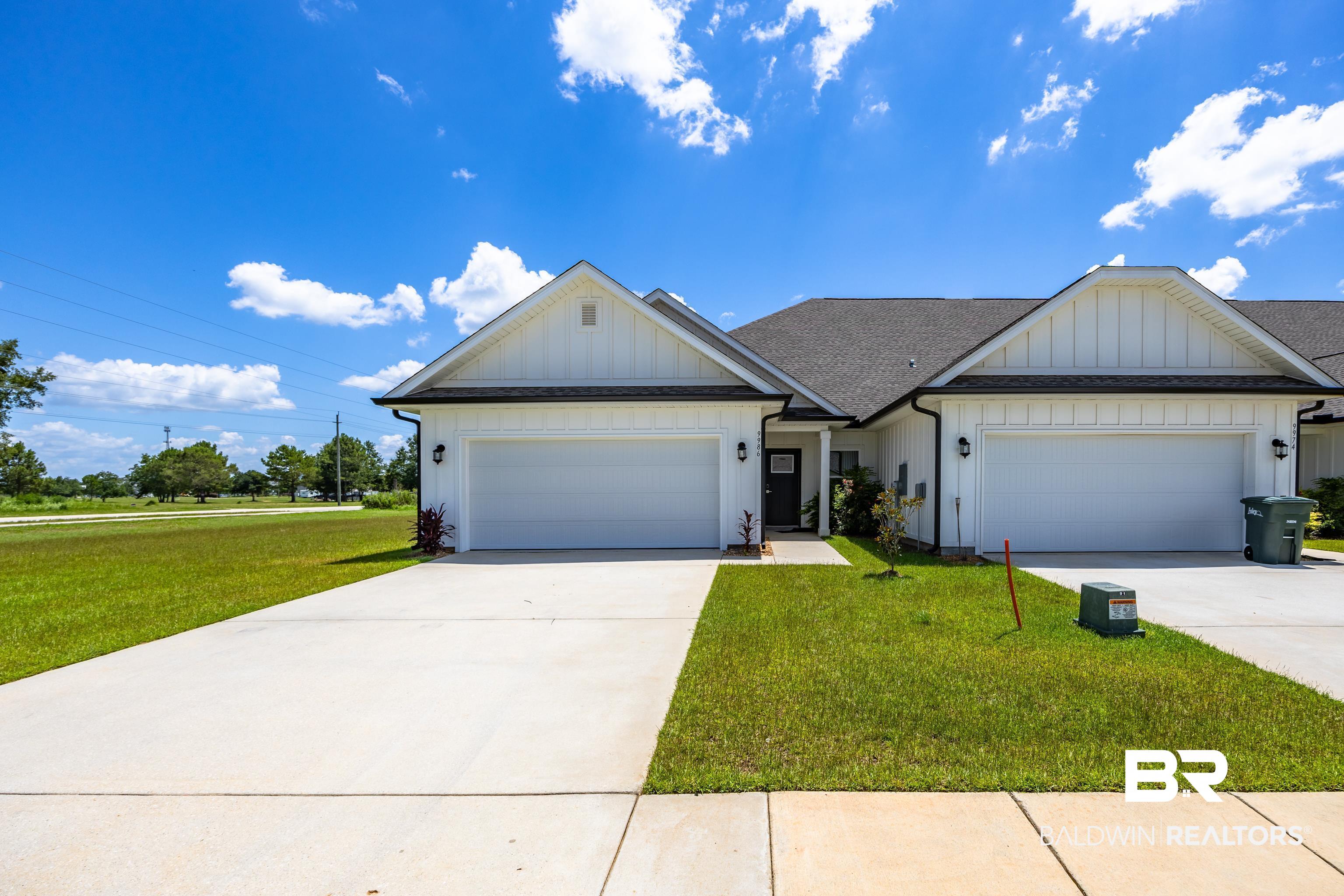 View of front of property with board and batten siding, a front lawn, an attached garage, and driveway