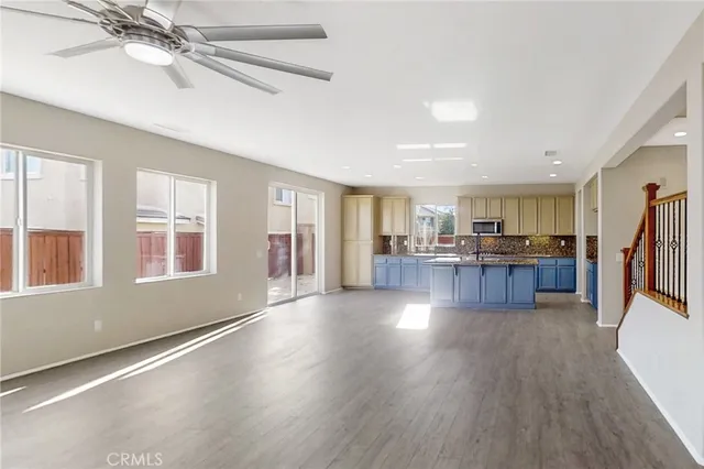 a open kitchen with stainless steel appliances granite countertop a refrigerator stove oven and a large window with wooden floor