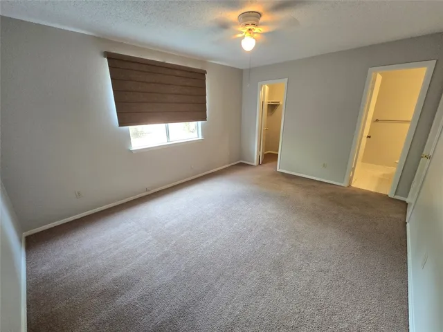 an empty room with a window and chandelier fan
