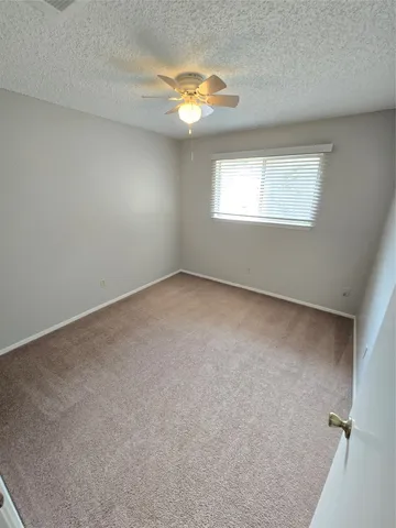 an empty room with windows and chandelier fan