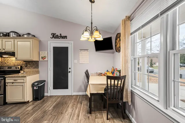 a kitchen with stainless steel appliances granite countertop a stove a refrigerator a microwave a dining table and chairs with wooden floor