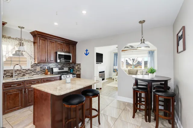 a kitchen with granite countertop a stove a sink dishwasher a dining table and chairs with wooden floor