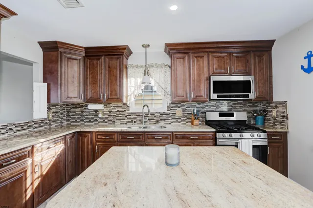 a kitchen with stainless steel appliances granite countertop a sink stove and microwave