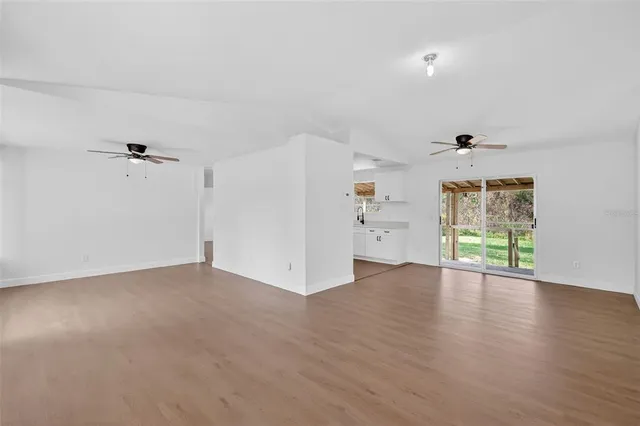 an empty room with wooden floor cabinet and windows