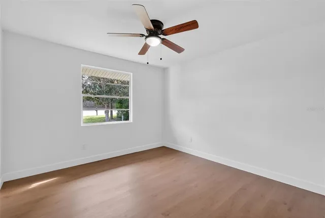 an empty room with a window and a fan