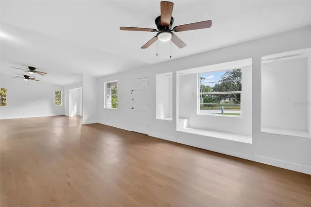 a view of an empty room with a window and wooden floor