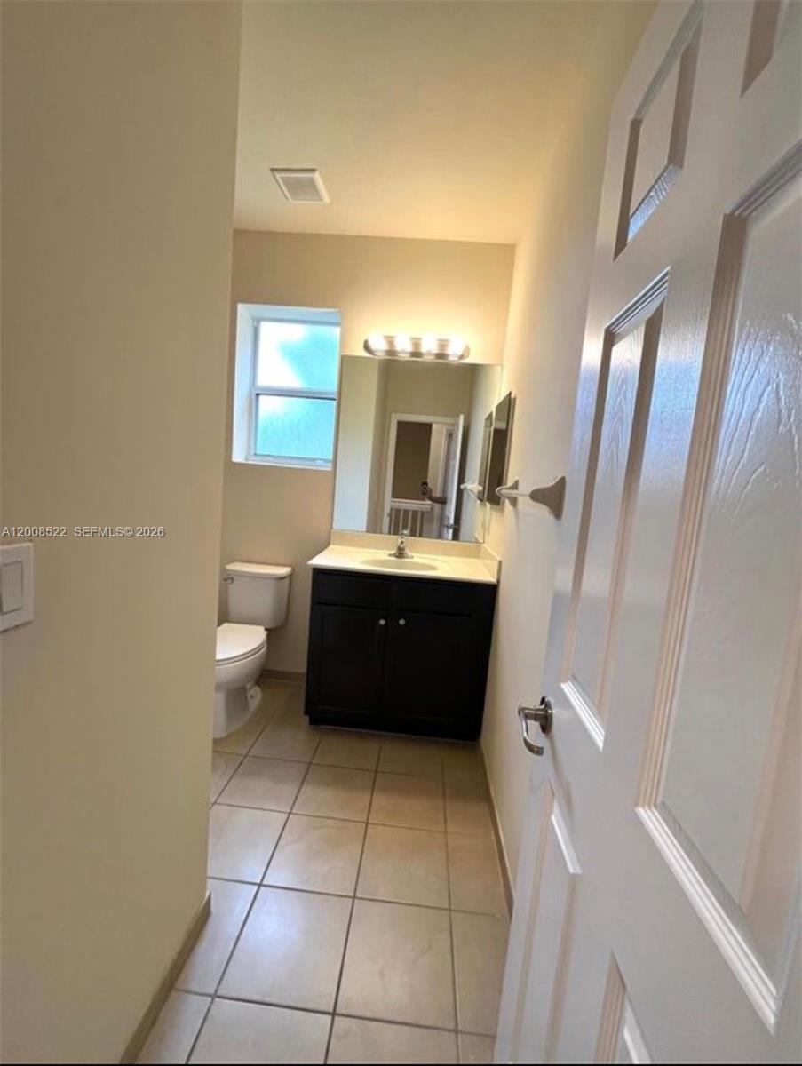 9401 Southwest 172nd Avenue, Unit 9401 Miami, FL 33196 - Photo 27 of 34 a bathroom with a sink a mirror and a toilet