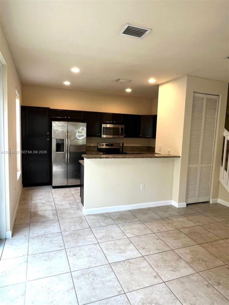 9401 Southwest 172nd Avenue, Unit 9401 Miami, FL 33196 - Photo 9 of 34 a view of a kitchen with a sink and an empty room