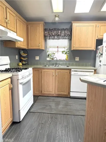 a kitchen with a stove a sink a window and cabinets