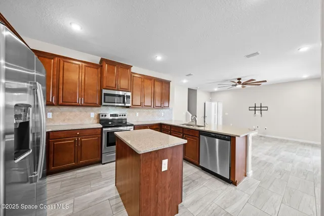 a kitchen with stainless steel appliances granite countertop a stove a sink dishwasher and a refrigerator