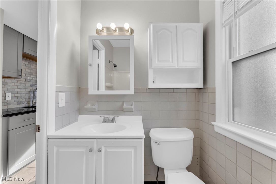 29034 Barjode Road Willowick, OH 44095 - Photo 14 of 24 Full bath featuring vanity, backsplash, a shower, tile walls, and light tile patterned floors