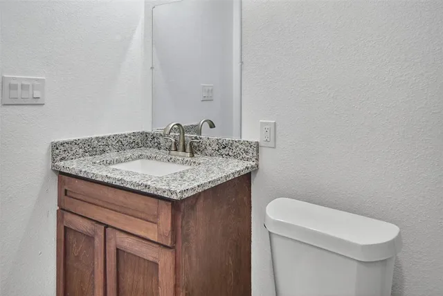 a bathroom with a granite countertop toilet a sink and a shower