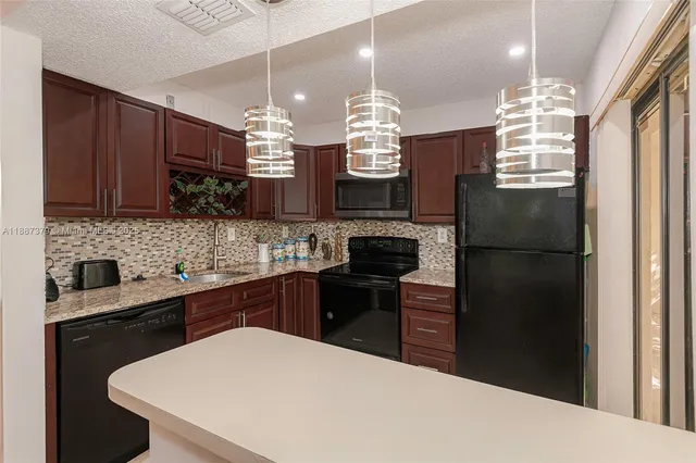 a kitchen with a refrigerator a sink dishwasher a kitchen island with wooden cabinets and floor