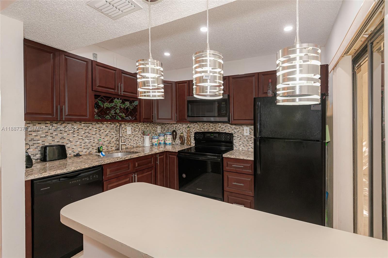20015 Northeast 3rd Court, Unit 6 Miami, FL 33179 - Photo 5 of 31 a kitchen with a refrigerator a sink dishwasher a kitchen island with wooden cabinets and floor