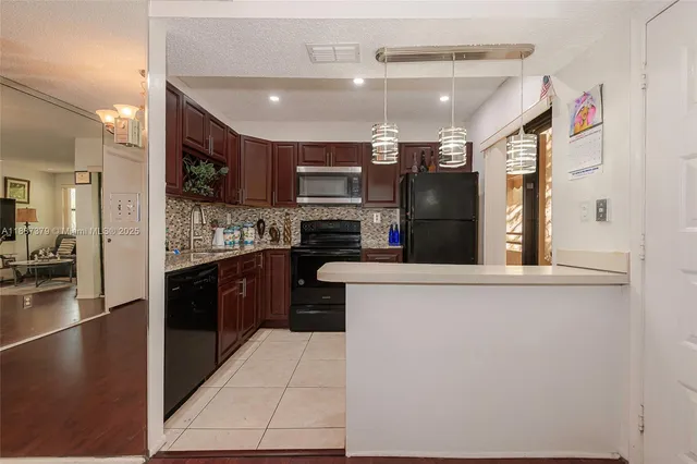 a kitchen with stainless steel appliances kitchen island granite countertop a refrigerator and a sink
