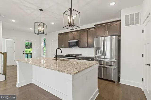 a kitchen with stainless steel appliances granite countertop a sink refrigerator and cabinets