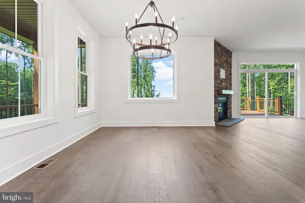 an empty room with wooden floor chandelier and windows