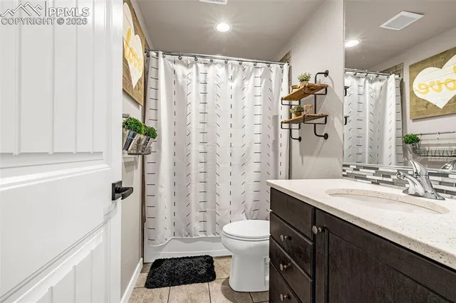 a bathroom with a sink a toilet a shower curtain and a large mirror