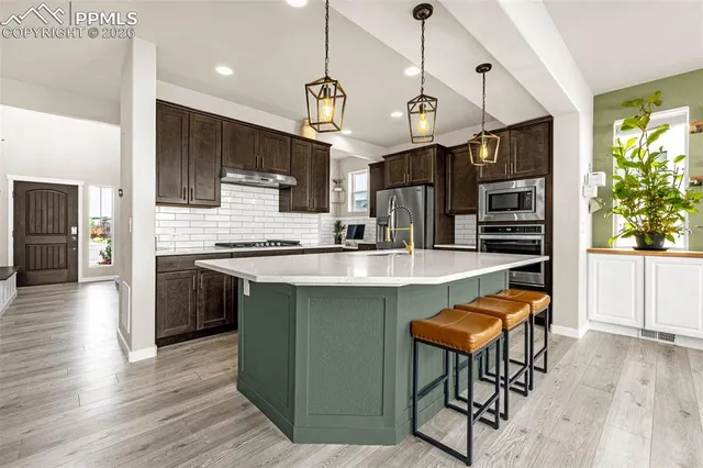 a kitchen with stainless steel appliances kitchen island granite countertop a table chairs in it and wooden floors