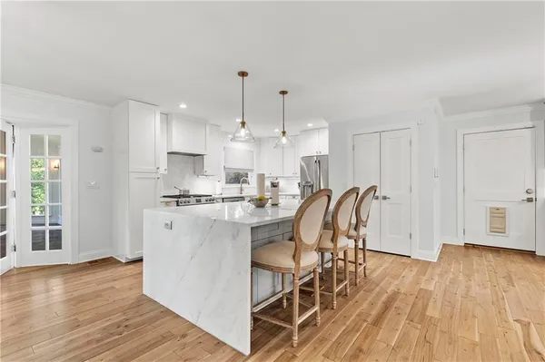 a kitchen with stainless steel appliances granite countertop a dining table chairs microwave and cabinets