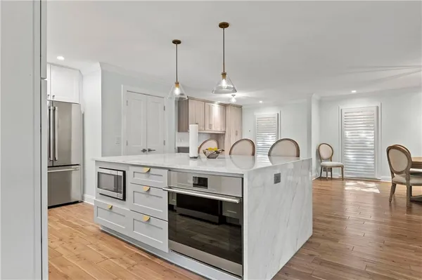 a open kitchen with stainless steel appliances granite countertop a stove a sink dishwasher a refrigerator and white cabinets with wooden floor