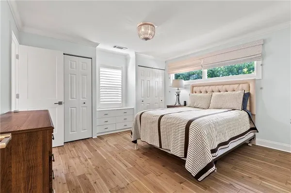 a spacious bedroom with a bed and wooden floor