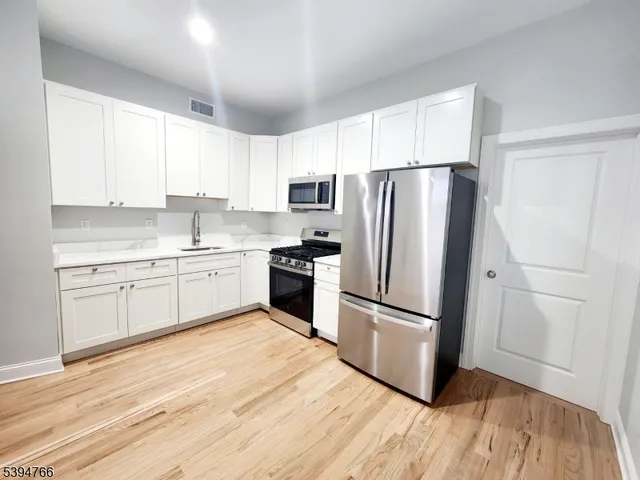 a kitchen with a refrigerator a sink and dishwasher with wooden floors