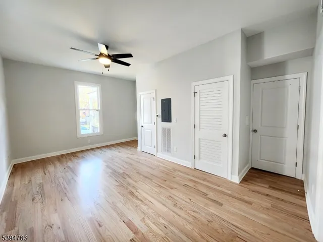 a view of an empty room with wooden floor and window