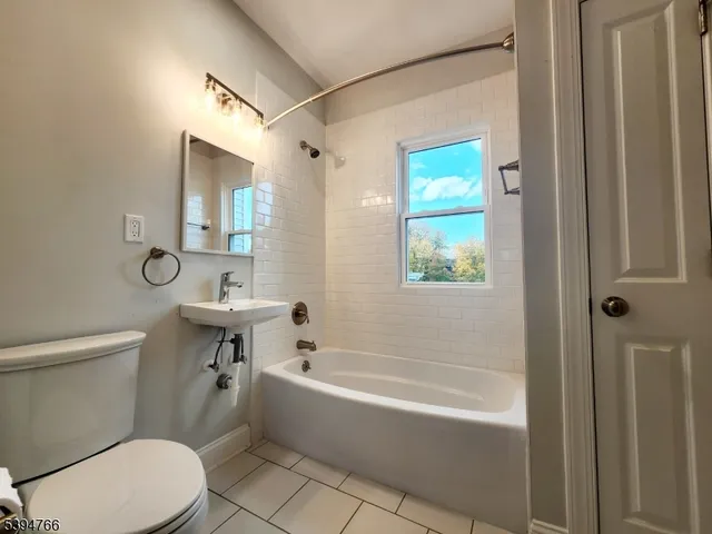 a bathroom with a sink a toilet a mirror a bathtub and shower