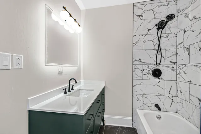 a bathroom with a sink and mirror with bathtub