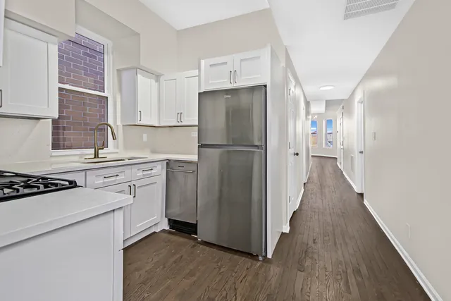 a kitchen with a refrigerator a stove top oven and wooden floor