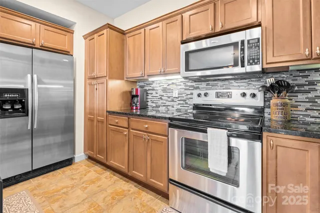 a kitchen with stainless steel appliances granite countertop a stove a microwave and a refrigerator