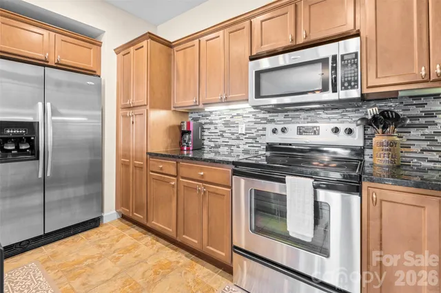 a kitchen with stainless steel appliances granite countertop a stove a microwave and a refrigerator