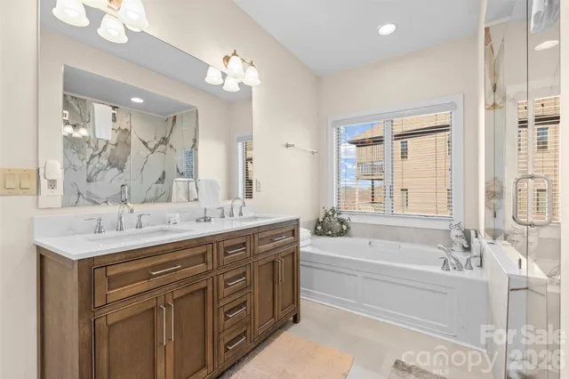 a bathroom with a granite countertop bathtub a sink and a large mirror
