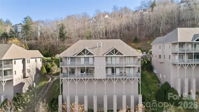 a view of a white house next to a yard with plants and trees