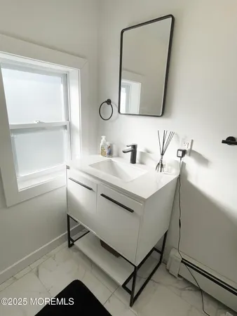 a bathroom with a sink mirror and a window