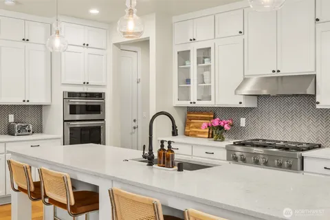 a kitchen with stainless steel appliances a stove a sink and white cabinets