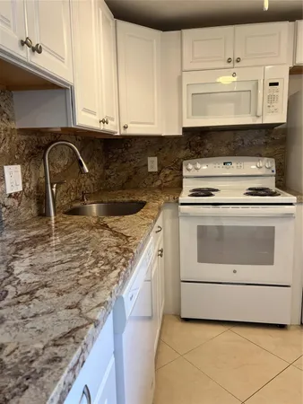 a kitchen with granite countertop a sink and a stove top oven