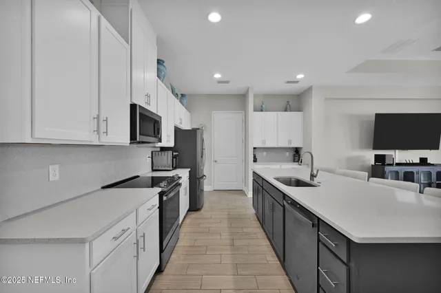 a kitchen with stainless steel appliances a sink dishwasher a stove top oven a refrigerator with grey cabinets