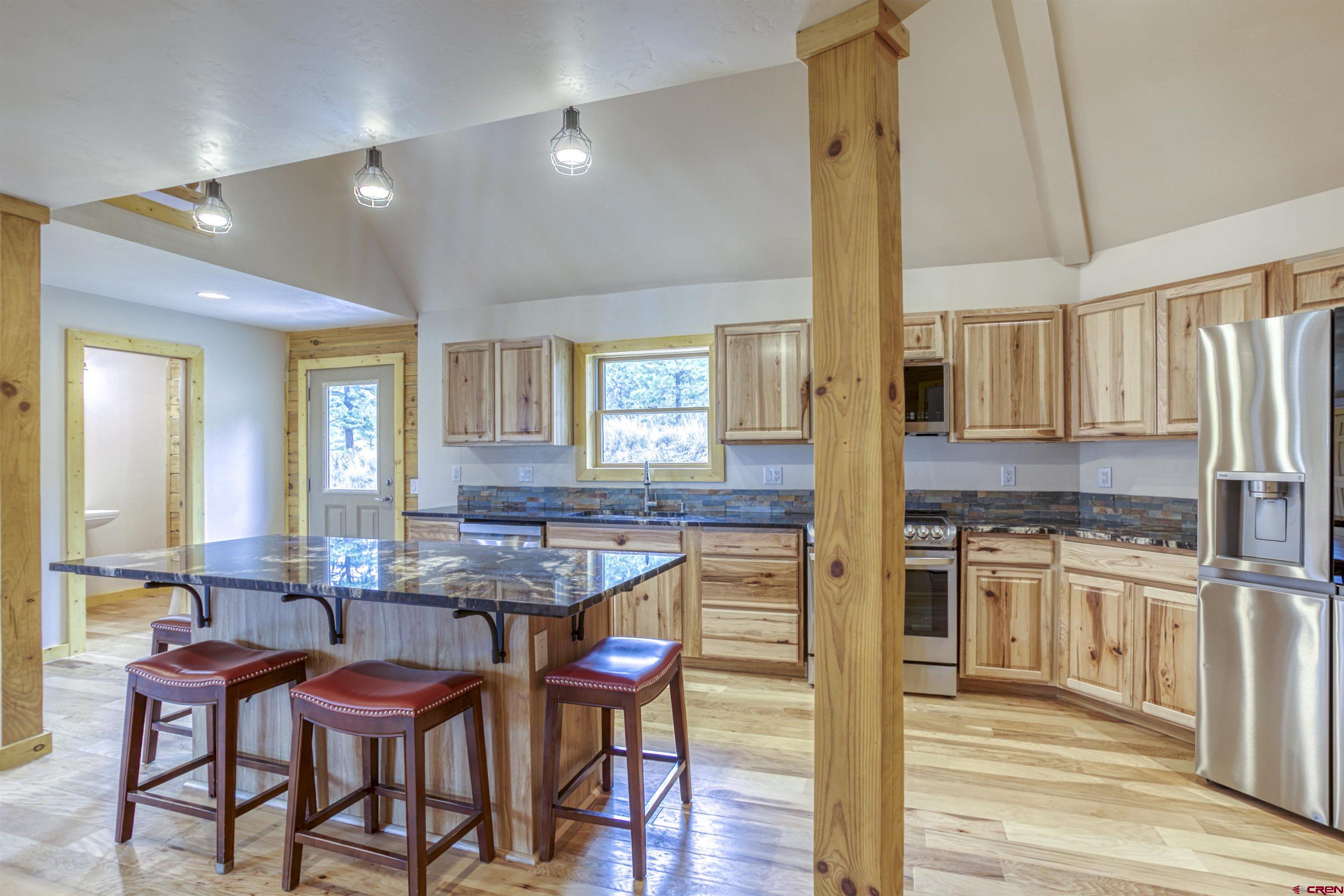 159 Snow Circle Pagosa Springs, CO 81147 - Photo 15 of 45 a kitchen with stainless steel appliances kitchen island granite countertop a table chairs and a refrigerator
