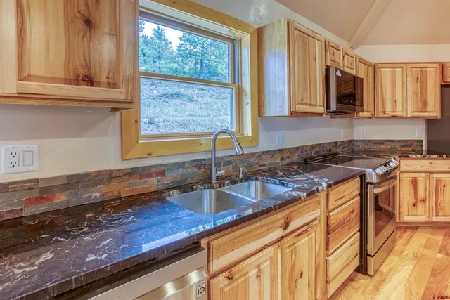 a kitchen with granite countertop a sink a stove and cabinets